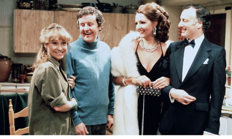 Cast of the classic British sitcom The Good Life, including Tom, Barbara, Margo and Jerry, standing together and smiling in a scene from the series.