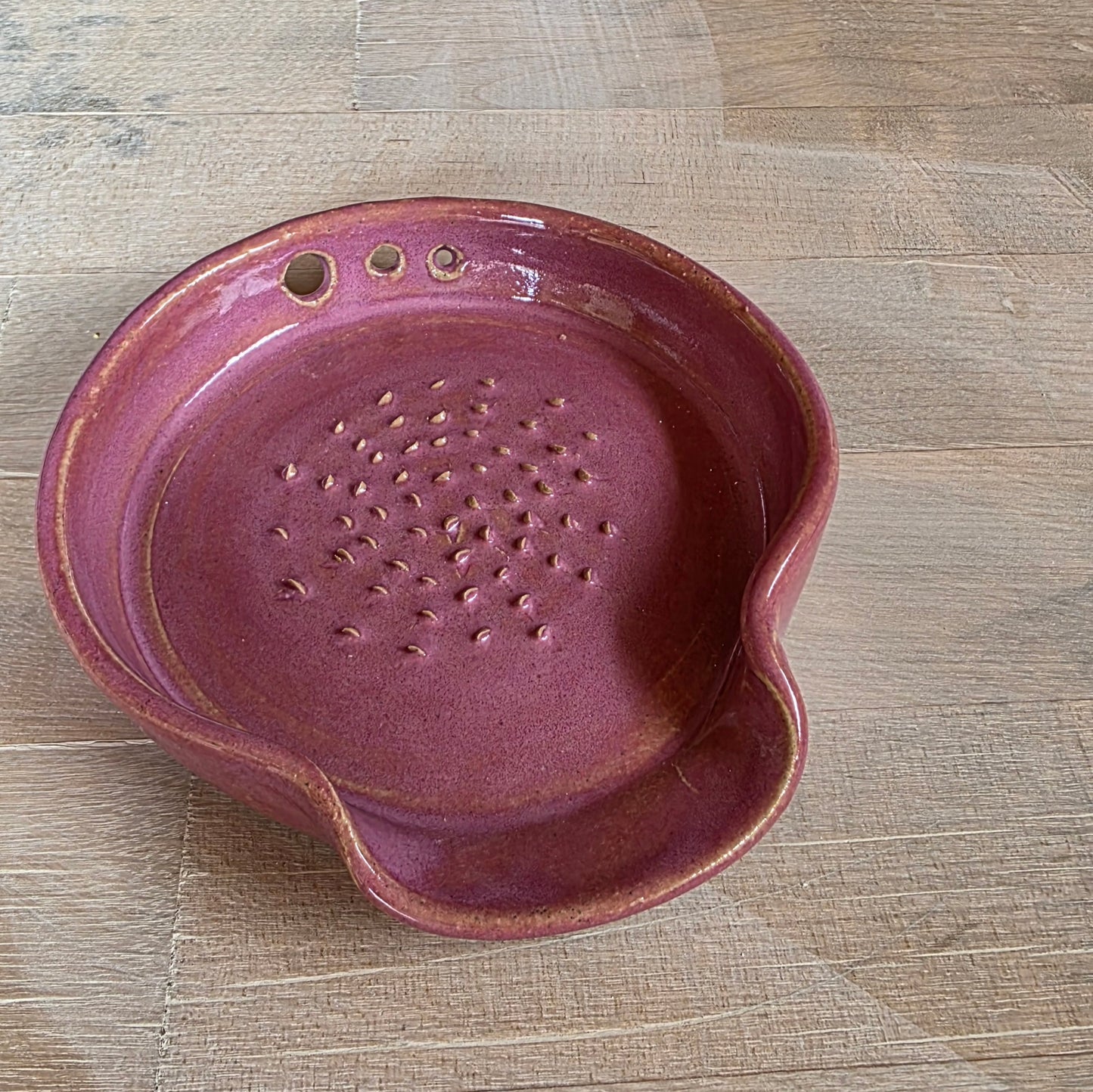pink ceramic garlic grater, herb stripper, spoon rest on wooden board