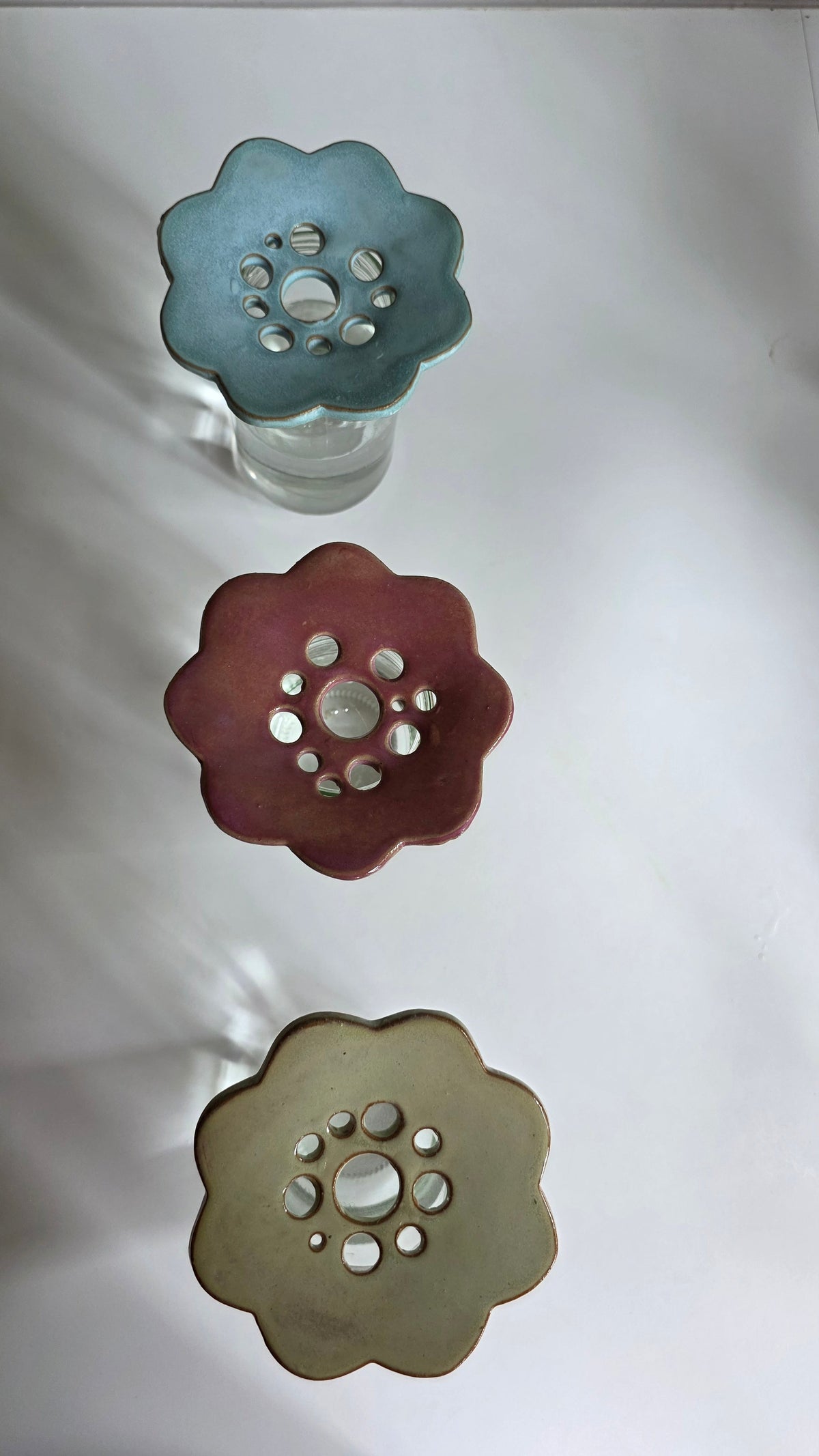Overhead view of ceramic flower frogs in rustic blue, pink and seagrass green showing scalloped shape and arrangement holes