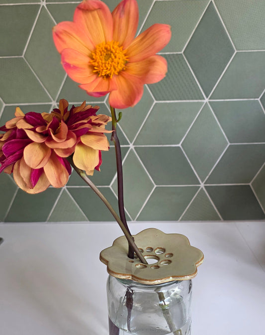 Seagrass green ceramic flower frog holding dahlias in a glass jar, green tile backdrop