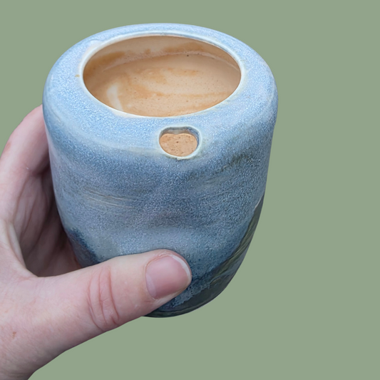 Coastal glaze ceramic takeaway tumbler held in hand with a latte, showing thumb notch and textured surface 